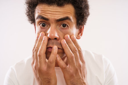 Tired mixed race adult man is looking at his eye bags.の写真素材