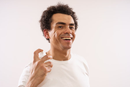 Handsome mixed race adult man is applying aftershave to his face.の写真素材