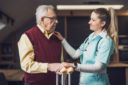 Nurse home caregiver is assisting old man at his home. Professional health support for elderly people.の写真素材