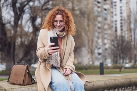 Portrait of a young redhead woman using mobile phone in the cityの写真素材