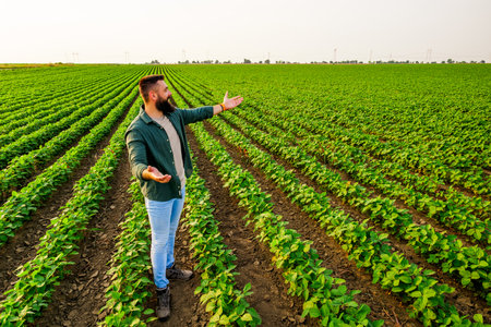 Portrait of farmer who is cultivating soybean. He is satisfied with good progress of plants. Agricultural occupation.の写真素材