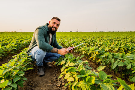 Portrait of farmer who is cultivating soybean. He is satisfied with good progress of plants. Agricultural occupation.の写真素材