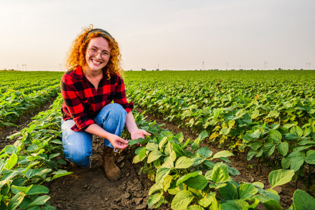 Portrait of female farmer who is cultivating soybean. She is satisfied with good progress of plants. Agricultural occupation.の写真素材