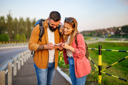Happy smiling couple are using maps on smartphone in the city. Tourists are sightseeing in the city.の写真素材