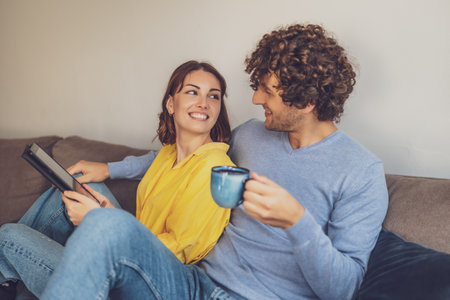 Portrait of young happy couple at home. They are relaxing at sofa.の写真素材