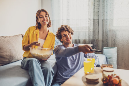 Portrait of young happy couple who is relaxing and watching TV at home.の写真素材
