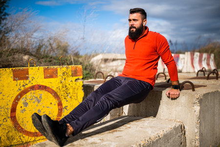 Young man is exercising outdoor. He is doing reverse push-ups.の写真素材