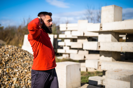 Adult man is exercising outdoor on sunny day. He is stretching his body.の写真素材