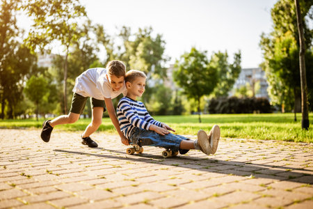 Two boys are having fun with skateboard in park. Playful children in park, happy childhood.の写真素材