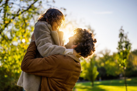 Portrait of happy loving couple in park in sunset. Man is holding his woman in hands.の写真素材