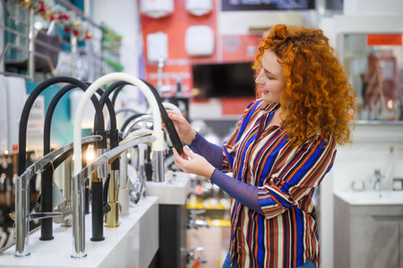 Portrait of salesperson in bathroom store. Happy redhead woman works in bath store. Sales...