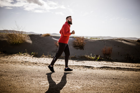 Adult man is jogging outdoor on sunny day.の写真素材