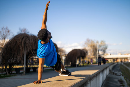 Young african-american man is exercising in the city. He is stretching his body.