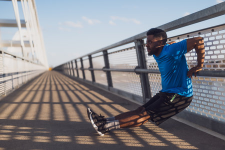Young african american athlete running on a bridge at sunrise.