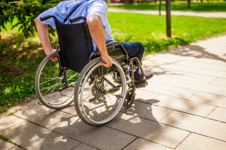 Close-up of disabled man in wheelchair walking in the park.