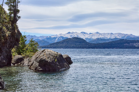 shore with green vegetation near a blue lake, on the horizon a landscape of mountains among a forest, Bariloche National Parkの写真素材