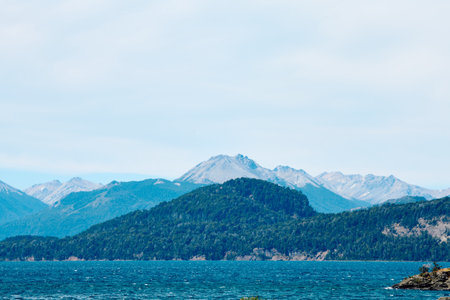shore with green vegetation near a blue lake, on the horizon a landscape of mountains among a forest, Bariloche National Parkの写真素材