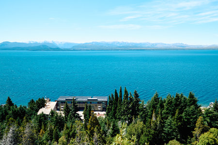 green forest on a mountainside near a blue lake with a city on the coast and mountain peaks in the distance, Bariloche dense National Parkの写真素材