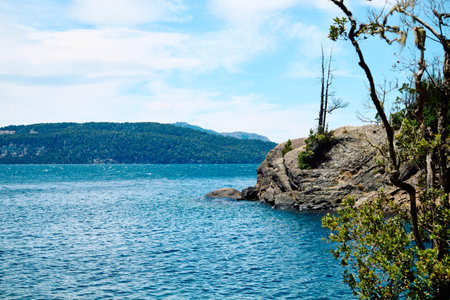 lonely trees on a rocky cliff against the backdrop of a lake and mountain peaks on the horizon, Bariloche National Parkの写真素材