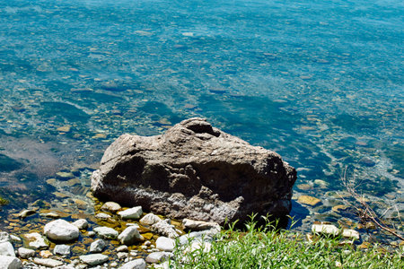 Rocky shore and green grass between the stones. Transparent turquoise water washes the shore.の写真素材