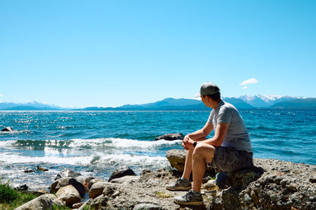 Traveling young man on a beautiful sunny day on the shore of a lake. Argentina. Patagoniaの写真素材
