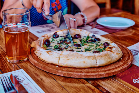 Female hands cutting pizza on the tableの写真素材