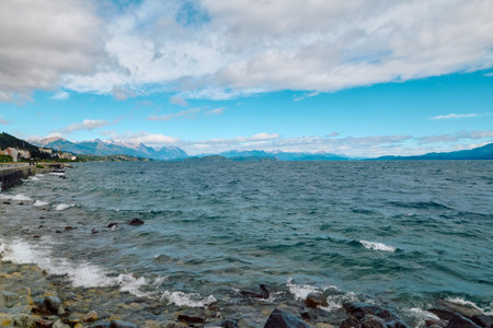 Huge lake with turquoise water surrounded by rocky mountains under blue, bright skyの写真素材