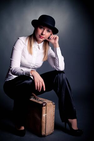 studio shot of gangster styled women sit on suitcaseの写真素材