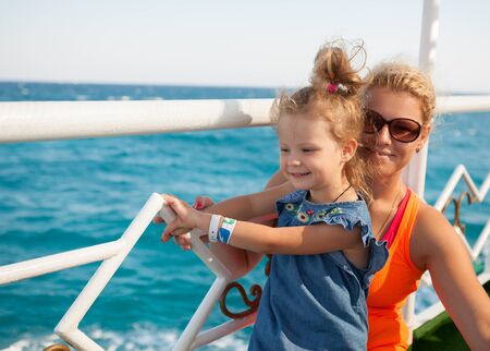 little girl with mother looking at blue seaの写真素材