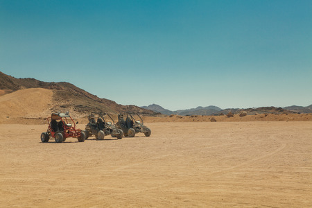 three atv standing in hot desert under clear skyの写真素材