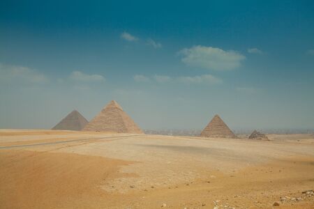 egyptian pyramids in heat yellow sands under clear skyの写真素材