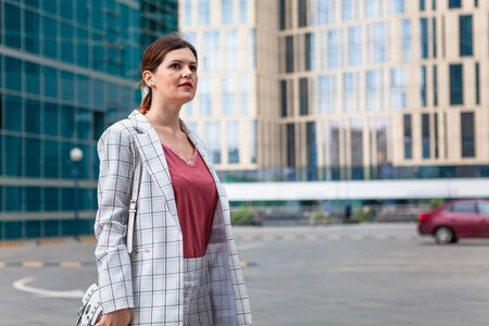 Young beautiful woman in checkered jacket in city backgroundの写真素材