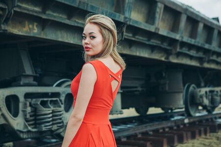 Asian young woman in red dress posing on cargo carriage background
