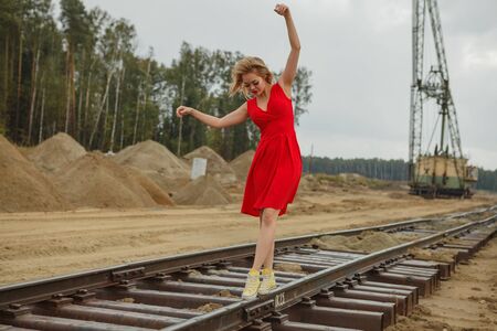 Young asian woman in red dress dancing on railwayの写真素材