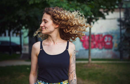 A curly-haired cute woman with tattoos on the streetの写真素材