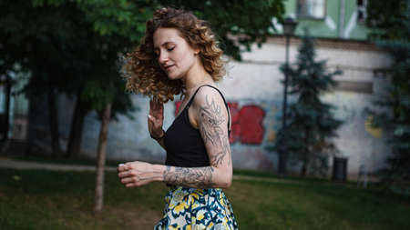 A curly-haired cute woman with tattoos on the streetの写真素材
