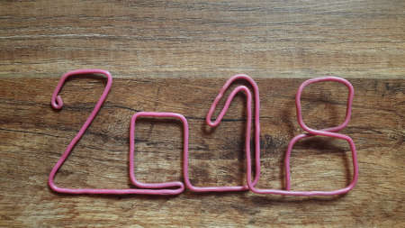 the red wire forms the number 2018 on a warm wooden backgroundの写真素材