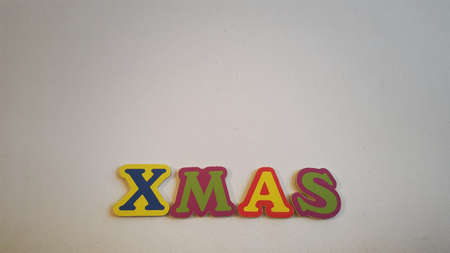 Colored letters spell out Xmas on white canvas with Christmas gifts.の写真素材