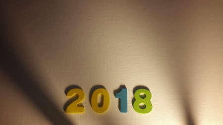Colored figures to form the number 2018 on white canvas with Christmas gifts