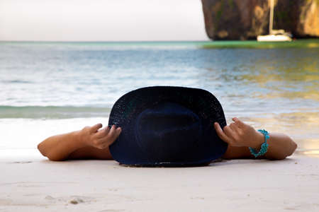 The girl in a hat lies on a beachの写真素材