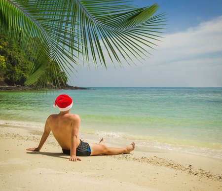 Man on the tropical beach in Santa Claus hatの写真素材