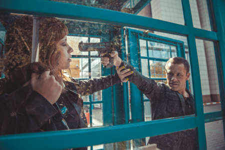 Crime. Robber with a gun threatening young beautiful girlの写真素材