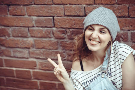 Young fashion beautiful hipster girl posing on the street near old brick wall backgroundの写真素材