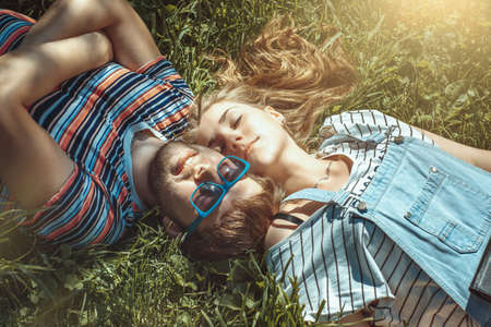 Happy smiling young couple lying on grass in the field. Concept love story.の写真素材