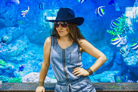 Woman in the background blue aquarium. Beautiful female model with copy space.
