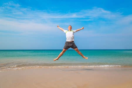 Happy tourist man jumping in a tropical beach. Travel concept and vacationsの写真素材