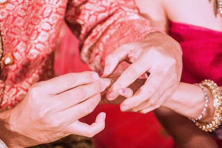 On the wedding day, the bride and groom have to exchange sweet together by pushing the ring together.の写真素材