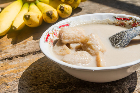 Banana in coconut milk is dessert on the table old wood background.の写真素材