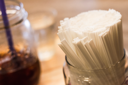 Straw is used for hot coffee, which is the background.の写真素材