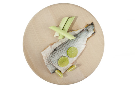 Carp fish on wooden plate with limeta and onion